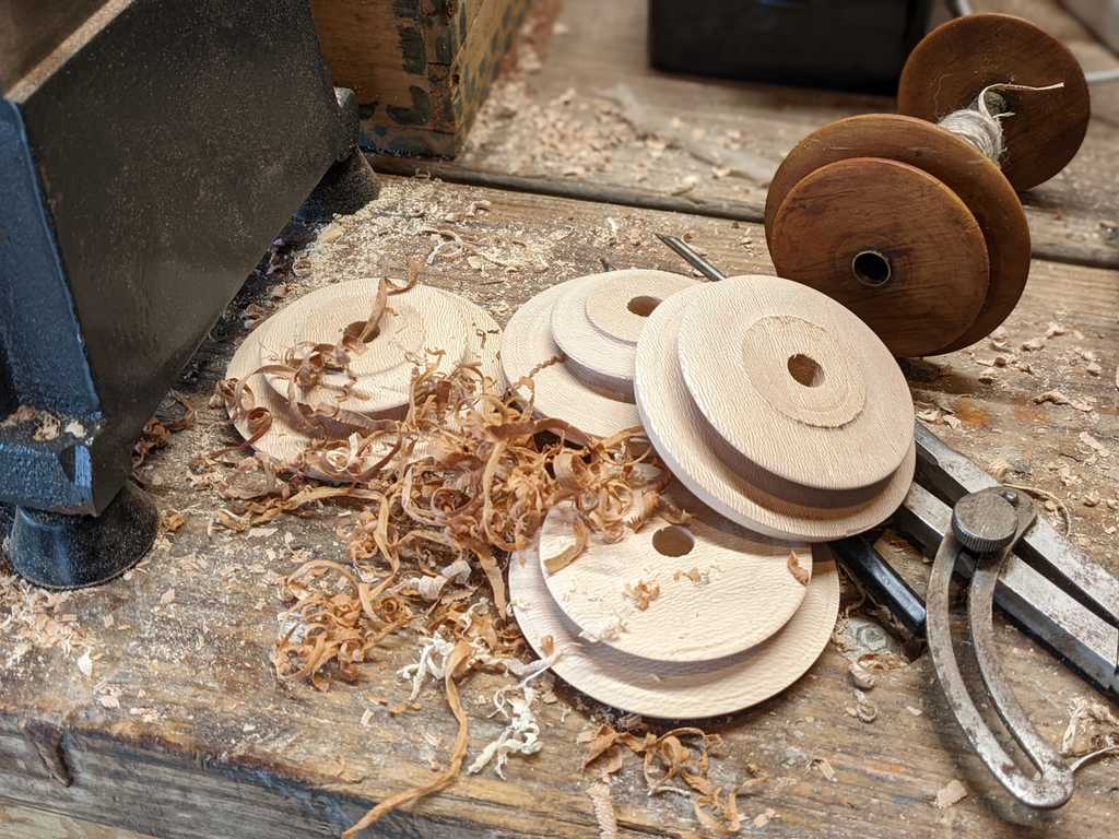 A pile of freshly made bobbin components, next to an old bobbin